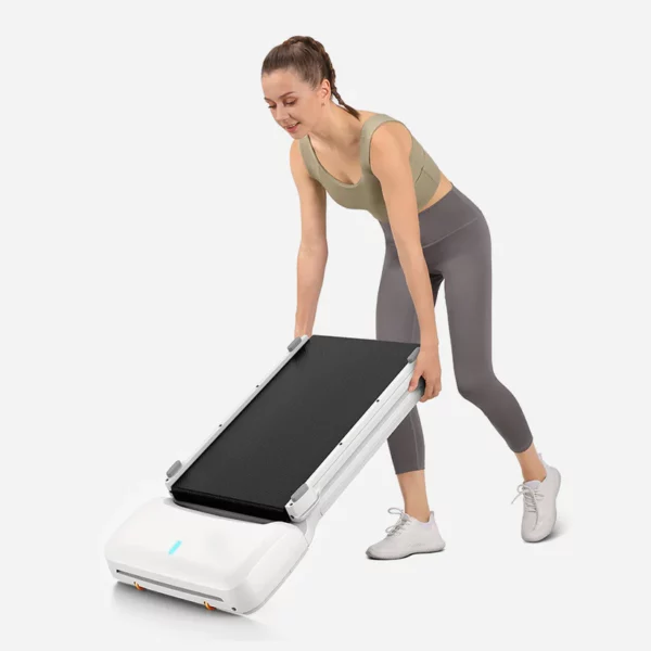 Une femme déplie un tapis de marche pliable et compact, idéal pour les petits espaces. Ce modèle innovant se range facilement après utilisation, offrant une solution pratique pour intégrer l'exercice physique dans votre routine quotidienne au bureau ou à la maison.