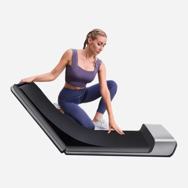 Femme ajustant un tapis de marche pliable et compact, idéal pour les environnements restreints. Facile à plier et à ranger, ce tapis de marche s'intègre parfaitement dans un mode de vie actif à domicile ou au bureau.