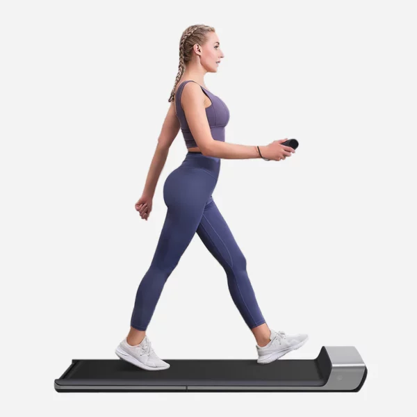 Femme en tenue de sport utilisant un tapis de marche compact et moderne, idéal pour une activité physique à faible impact au bureau ou à la maison, tout en optimisant son espace de travail.