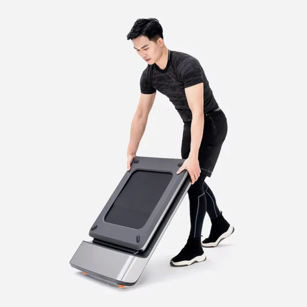 Homme pliant un tapis de marche compact et moderne. Ce design innovant facilite le rangement et le transport, idéal pour intégrer l'exercice physique dans un environnement de travail ou à domicile.